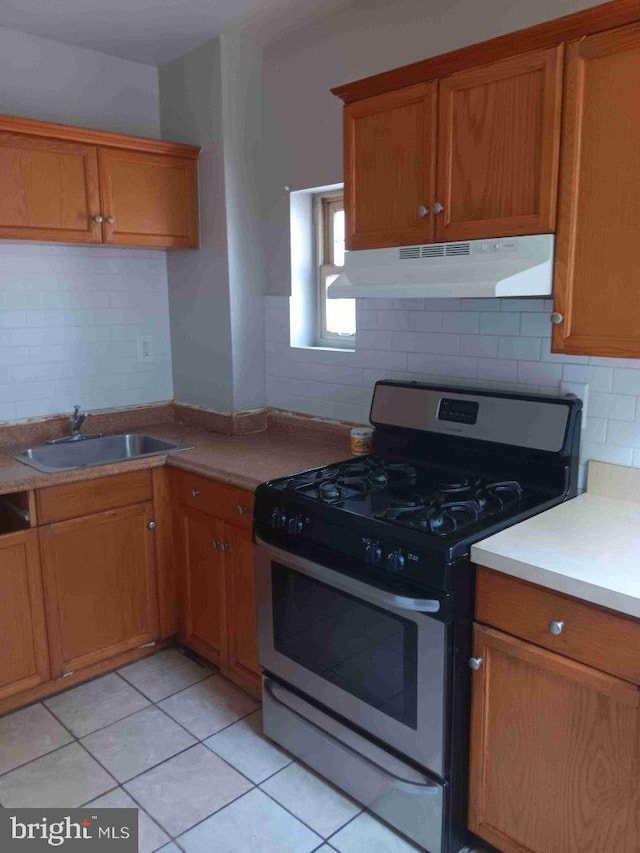 509 N Highland Ave, Baltimore, MD 21205 - kitchen featuring stainless steel range with gas cooktop, under cabinet range hood, decorative backsplash, and brown cabinetry