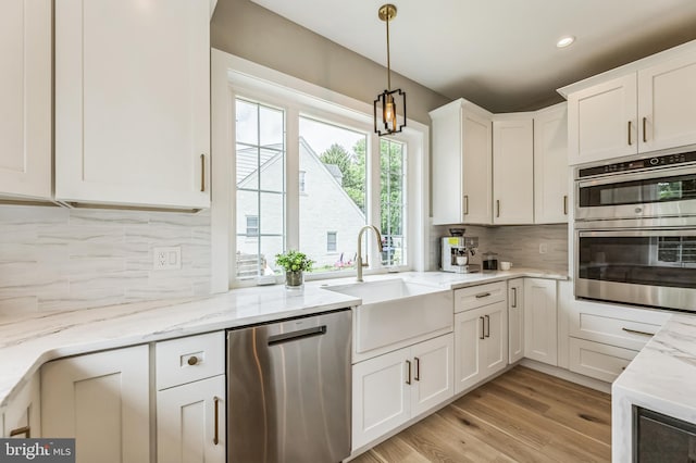 45 Orchard Ln, Berwyn, PA 19312 - kitchen with appliances with stainless steel finishes, white cabinetry, backsplash, pendant lighting, and light wood-style flooring