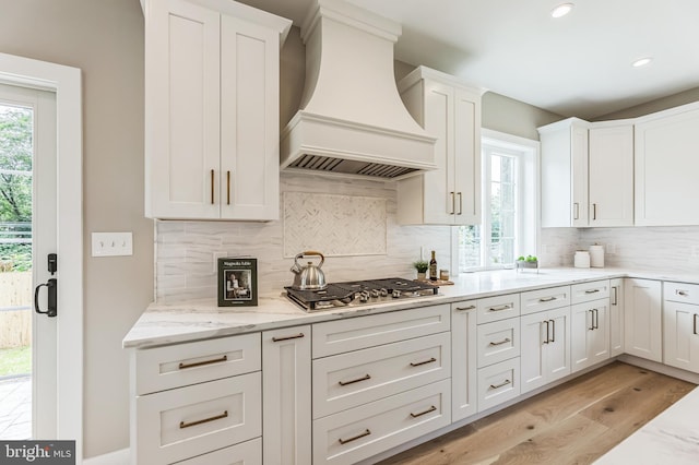 45 Orchard Ln, Berwyn, PA 19312 - kitchen featuring custom range hood, stainless steel gas cooktop, white cabinetry, light wood-type flooring, and light stone countertops