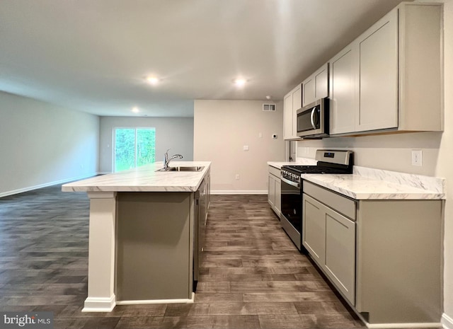 22189 Shorebird Way, Millsboro, DE 19966 - kitchen with stainless steel appliances, dark wood-style flooring, an island with sink, recessed lighting, and gray cabinets