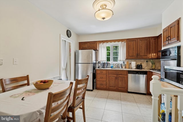 709 Parmentier Rd, Warminster, PA 18974 - kitchen featuring appliances with stainless steel finishes, tasteful backsplash, light tile patterned floors, brown cabinetry, and light stone countertops
