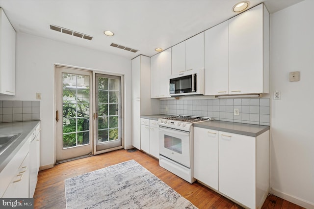 2205 Pine St, Philadelphia, PA 19103 - kitchen with white gas range, decorative backsplash, recessed lighting, white cabinetry, and light wood-type flooring