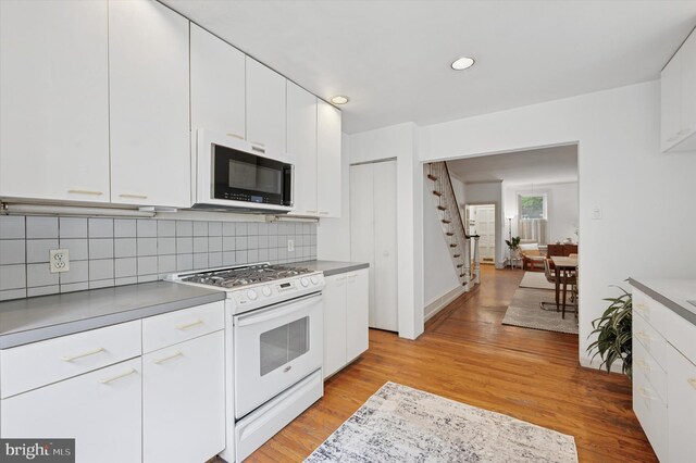 2205 Pine St, Philadelphia, PA 19103 - kitchen featuring gas range gas stove, white cabinets, light wood-style floors, tasteful backsplash, and light countertops