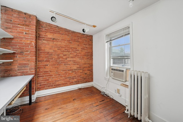 2205 Pine St, Philadelphia, PA 19103 - unfurnished dining area with radiator heating unit, hardwood / wood-style floors, cooling unit, track lighting, and brick wall