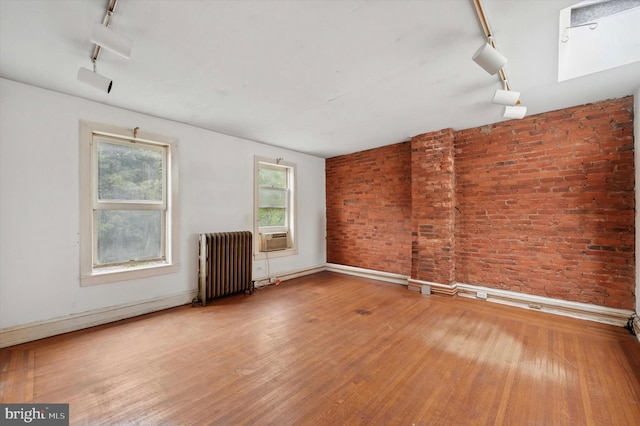 2205 Pine St, Philadelphia, PA 19103 - empty room with radiator heating unit, rail lighting, wood finished floors, brick wall, and cooling unit