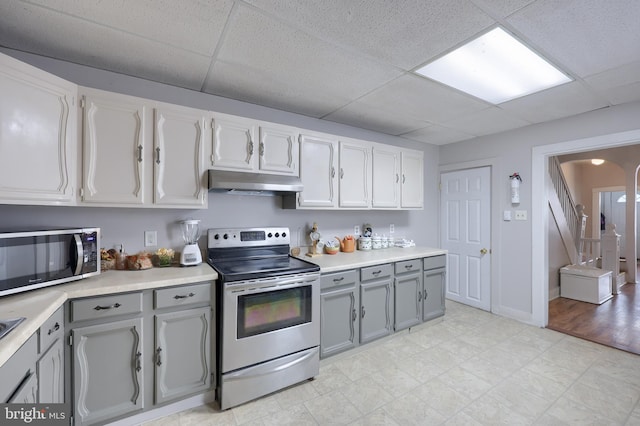 68 Locust St, Lancaster, PA 17602 - kitchen with appliances with stainless steel finishes, gray cabinetry, under cabinet range hood, a paneled ceiling, and light countertops