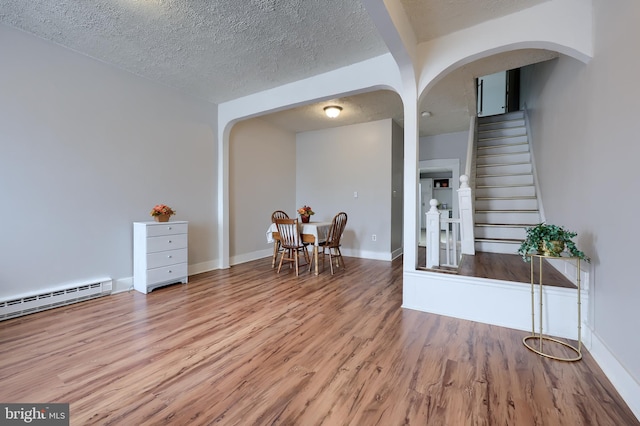 68 Locust St, Lancaster, PA 17602 - living area with arched walkways, wood finished floors, baseboard heating, a textured ceiling, and stairway