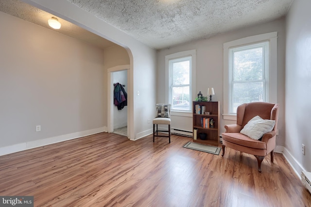 68 Locust St, Lancaster, PA 17602 - sitting room with wood finished floors, a textured ceiling, a baseboard radiator, arched walkways, and a baseboard heating unit