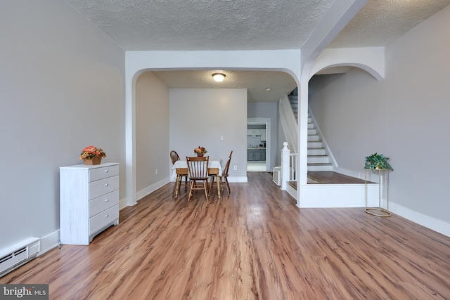 68 Locust St, Lancaster, PA 17602 - dining area featuring baseboard heating, arched walkways, stairs, light wood-style flooring, and a textured ceiling