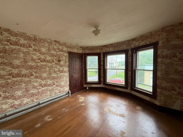 77 Spring St, Beaver Springs, PA 17812 - unfurnished room with wallpapered walls, a baseboard radiator, wood-type flooring, healthy amount of natural light, and a textured ceiling