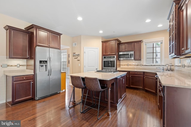 5696 Liberty Manor Cir, Woodbridge, VA 22193 - kitchen with stainless steel appliances, dark wood finished floors, a breakfast bar area, decorative backsplash, and light stone counters