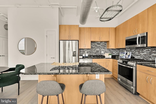 301 Massachusetts Ave NW Unit 1103, Washington, DC 20001 - kitchen featuring stainless steel appliances, light wood-type flooring, a kitchen breakfast bar, tasteful backsplash, and a high ceiling