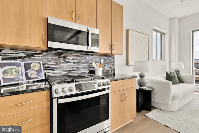 301 Massachusetts Ave NW Unit 1103, Washington, DC 20001 - kitchen with appliances with stainless steel finishes, dark stone countertops, backsplash, light wood finished floors, and light brown cabinetry