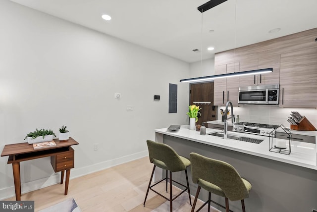 1471 Harvard St NW Unit 2, Washington, DC 20009 - kitchen with stainless steel microwave, a kitchen breakfast bar, modern cabinets, electric panel, and light countertops