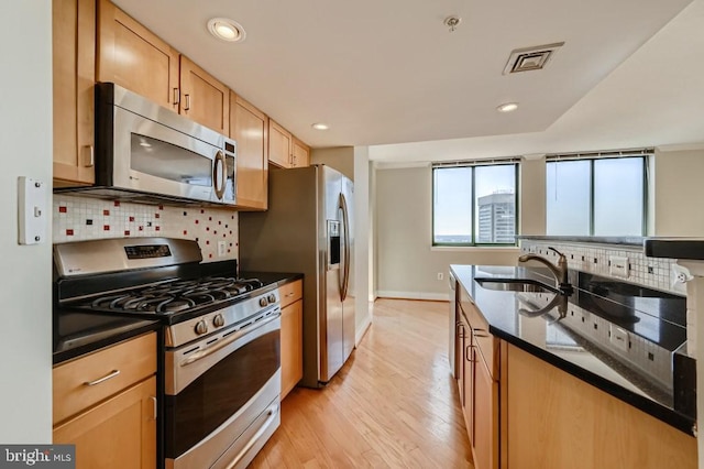 414 Water St Unit 2814, Baltimore, MD 21202 - kitchen featuring appliances with stainless steel finishes, backsplash, light wood-type flooring, recessed lighting, and dark stone counters
