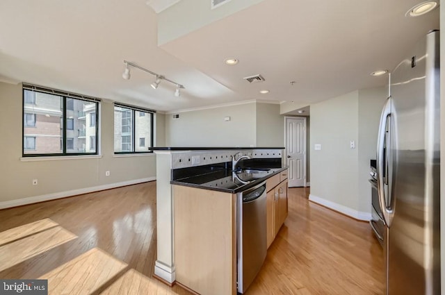 414 Water St Unit 2814, Baltimore, MD 21202 - kitchen with stainless steel appliances, an island with sink, light wood-style flooring, dark countertops, and rail lighting