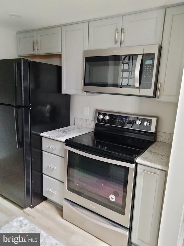 14007 Vista Dr Unit 30, Laurel, MD 20707 - kitchen featuring stainless steel appliances, light wood-style flooring, and light stone counters