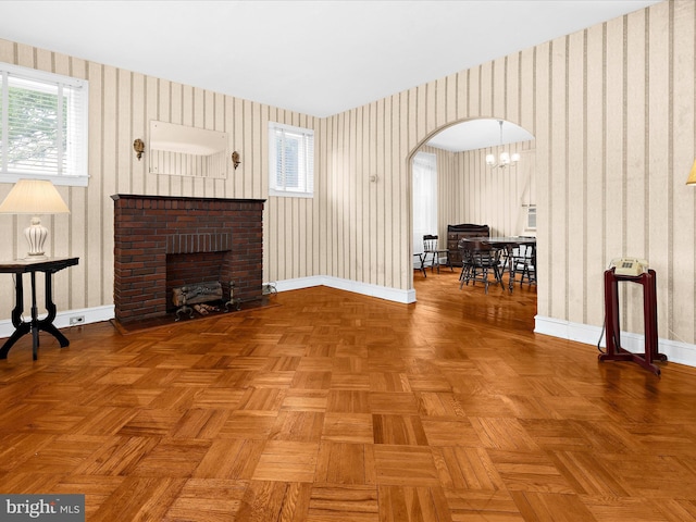 5000 Levindale Rd, Baltimore, MD 21215 - living room featuring arched walkways, wallpapered walls, a fireplace, and a chandelier
