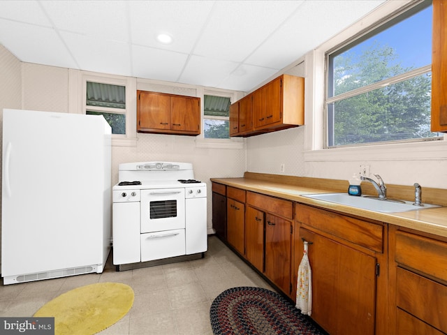 5000 Levindale Rd, Baltimore, MD 21215 - kitchen with white appliances, light countertops, brown cabinets, a paneled ceiling, and light tile patterned flooring
