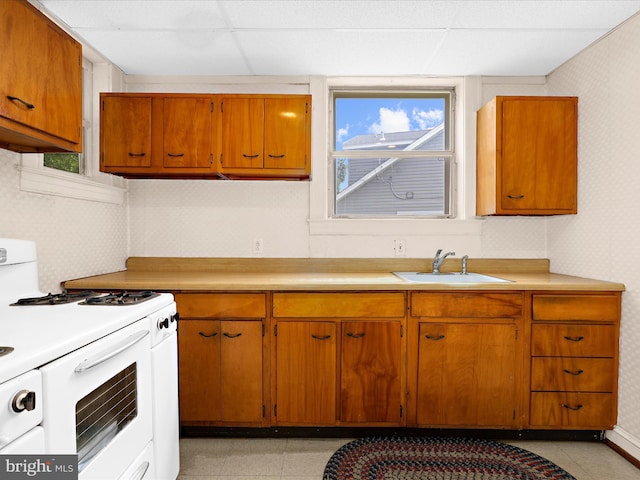 5000 Levindale Rd, Baltimore, MD 21215 - kitchen with white range with gas cooktop, light countertops, wallpapered walls, brown cabinetry, and a drop ceiling