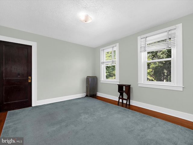 5000 Levindale Rd, Baltimore, MD 21215 - unfurnished room with radiator heating unit, dark wood-style floors, a textured ceiling, and dark colored carpet