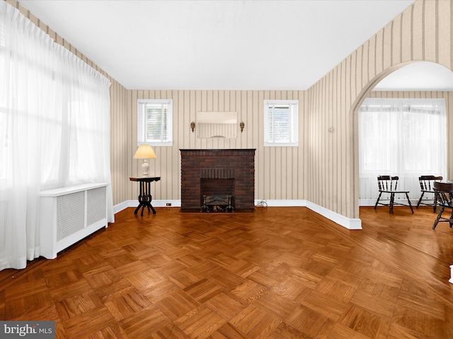 5000 Levindale Rd, Baltimore, MD 21215 - living area featuring wallpapered walls, arched walkways, a fireplace, and radiator heating unit