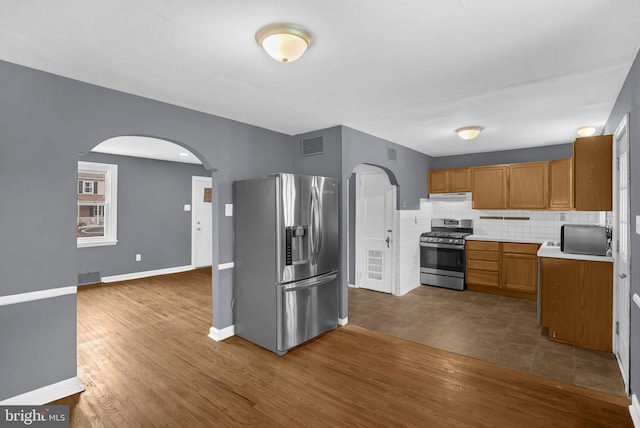 1233 E Ave, Abington, PA 19001 - kitchen with stainless steel appliances, arched walkways, tasteful backsplash, dark wood finished floors, and under cabinet range hood