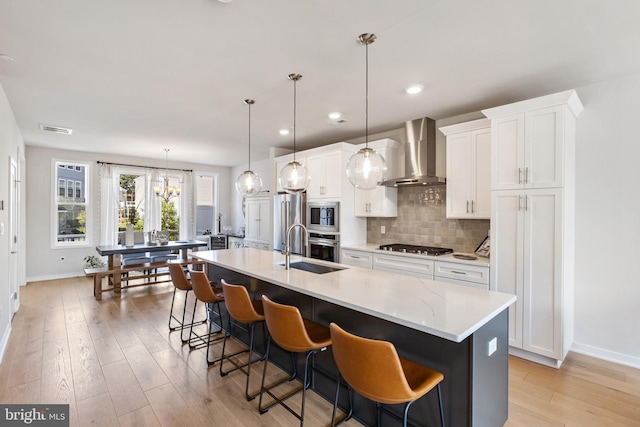 324 Star Tavern Ln, West Chester, PA 19382 - kitchen with wall chimney exhaust hood, light wood-type flooring, white cabinets, an island with sink, and tasteful backsplash