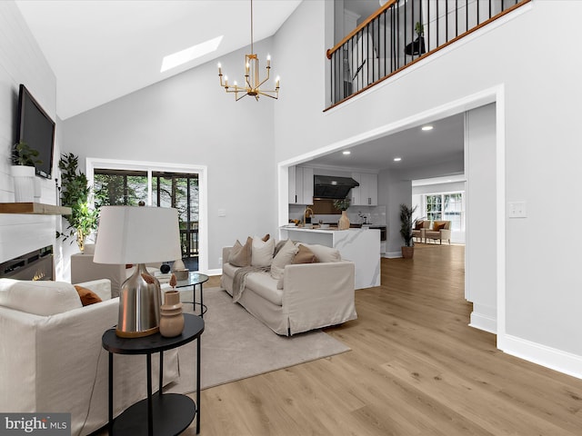 9300 Bellbeck Rd, Baltimore, MD 21234 - living room with a glass covered fireplace, light wood-style floors, a chandelier, high vaulted ceiling, and a skylight