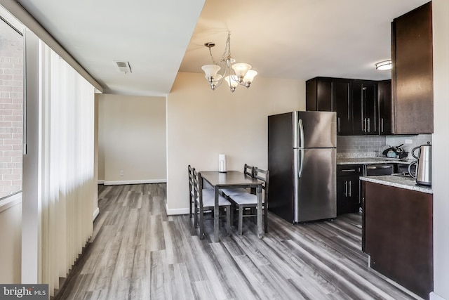 5851 Quantrell Ave Unit 407, Alexandria, VA 22312 - kitchen with freestanding refrigerator, light wood-style floors, a chandelier, decorative backsplash, and light stone countertops