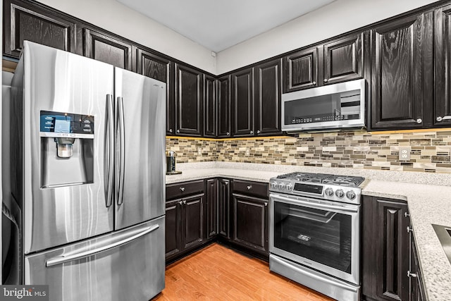 605 N Atlantic Ave Unit 104, Collingswood, NJ 08108 - kitchen featuring stainless steel appliances, dark cabinets, light wood finished floors, backsplash, and light stone counters