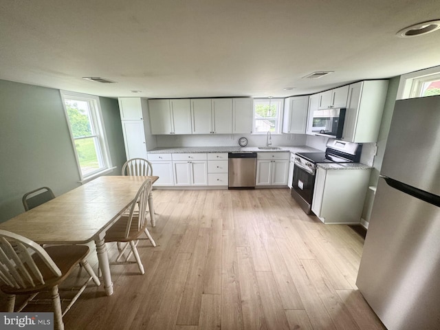 6054 Baltimore Pike, Littlestown, PA 17340 - kitchen with appliances with stainless steel finishes, light wood-style floors, plenty of natural light, and white cabinetry