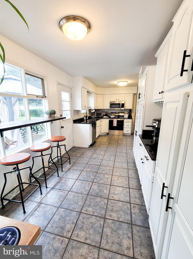 353 Wedgewood Dr, Easton, PA 18045 - kitchen featuring appliances with stainless steel finishes, dark countertops, white cabinetry, and decorative backsplash