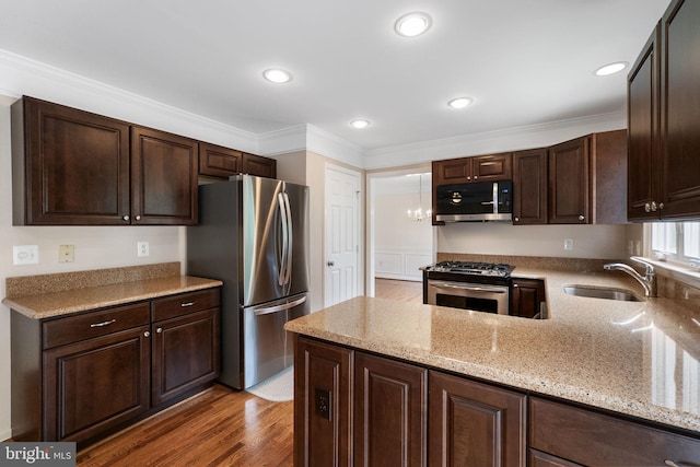 21411 Emerald Dr, Germantown, MD 20876 - kitchen with stainless steel appliances, dark brown cabinetry, wood finished floors, light stone counters, and crown molding