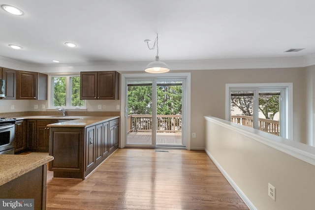 21411 Emerald Dr, Germantown, MD 20876 - kitchen with light countertops, dark brown cabinets, stainless steel electric stove, light wood finished floors, and decorative light fixtures