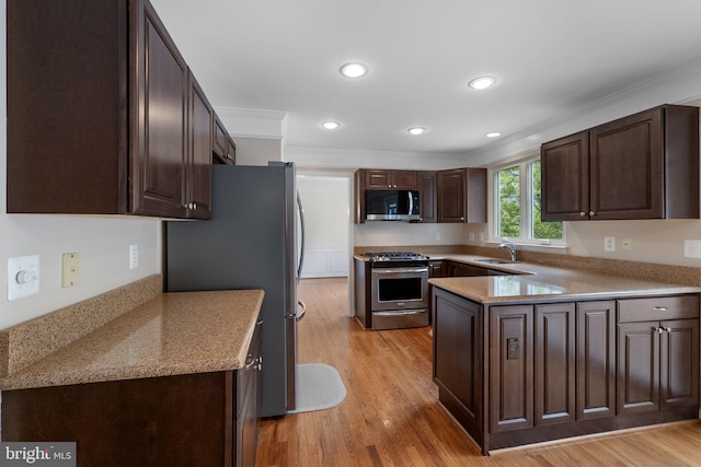 21411 Emerald Dr, Germantown, MD 20876 - kitchen with appliances with stainless steel finishes, dark brown cabinetry, ornamental molding, light wood-type flooring, and a peninsula