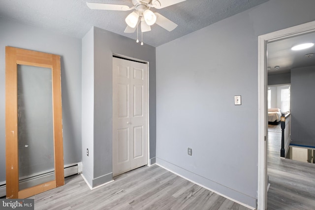 624 S Heald St, Wilmington, DE 19801 - unfurnished bedroom featuring baseboard heating, light wood finished floors, a closet, a ceiling fan, and a textured ceiling