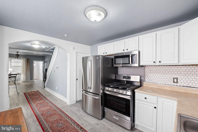 624 S Heald St, Wilmington, DE 19801 - kitchen with stainless steel appliances, arched walkways, light countertops, white cabinets, and light wood-style flooring