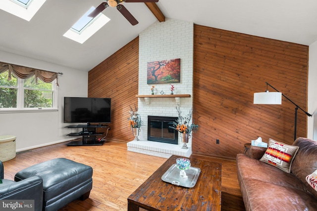 6212 Monroe Ave, Sykesville, MD 21784 - living area featuring ceiling fan, wooden walls, a skylight, a brick fireplace, and wood finished floors