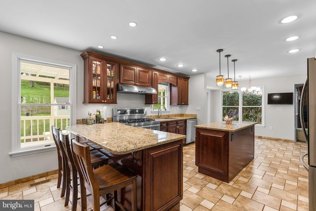 6212 Monroe Ave, Sykesville, MD 21784 - kitchen featuring appliances with stainless steel finishes, under cabinet range hood, a peninsula, a center island, and plenty of natural light