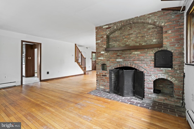 210 S Pennell Rd, Media, PA 19063 - unfurnished living room with a fireplace, wood-type flooring, stairway, and a baseboard heating unit