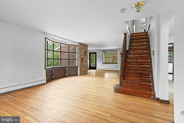 210 S Pennell Rd, Media, PA 19063 - unfurnished living room with baseboard heating, wood-type flooring, arched walkways, and a baseboard heating unit