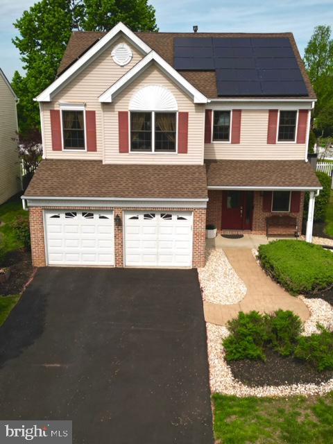 4 Sandstone Rd, East Windsor, NJ 08520 - view of front of property featuring a porch, brick siding, asphalt driveway, a garage, and roof mounted solar panels