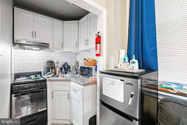 523 W Venango St, Philadelphia, PA 19140 - kitchen featuring black gas range oven, under cabinet range hood, fridge, and white cabinets