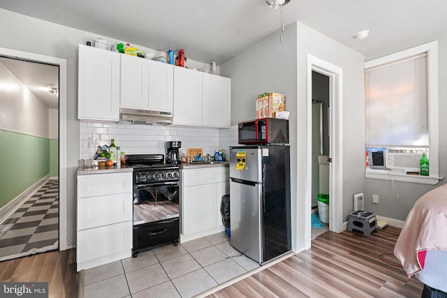 523 W Venango St, Philadelphia, PA 19140 - kitchen with freestanding refrigerator, black range, under cabinet range hood, white cabinets, and decorative backsplash