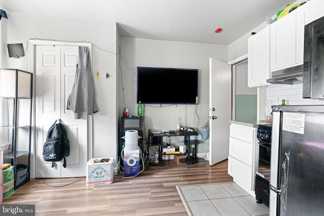 523 W Venango St, Philadelphia, PA 19140 - kitchen with under cabinet range hood, white cabinets, freestanding refrigerator, tasteful backsplash, and light wood-type flooring