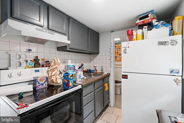 523 W Venango St, Philadelphia, PA 19140 - kitchen with white appliances, under cabinet range hood, gray cabinets, light tile patterned flooring, and dark countertops
