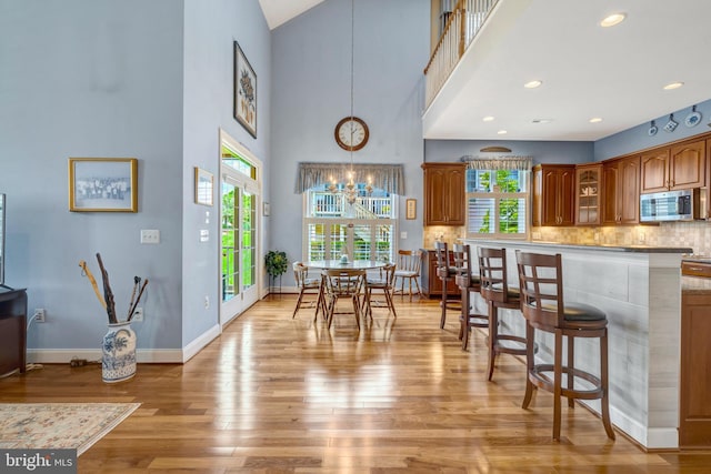 5230 Canyon Creek Way, Haymarket, VA 20169 - kitchen with stainless steel microwave, light wood-type flooring, a kitchen bar, a chandelier, and brown cabinetry