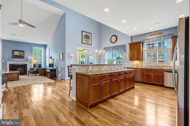 5230 Canyon Creek Way, Haymarket, VA 20169 - kitchen with light wood-style flooring, high vaulted ceiling, appliances with stainless steel finishes, a ceiling fan, and decorative backsplash