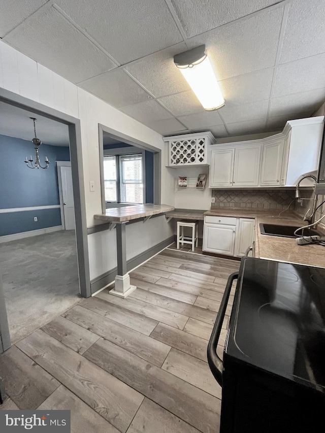 217 Bartlett Ave, Sharon Hill, PA 19079 - kitchen featuring light wood-style floors, black / electric stove, white cabinetry, a chandelier, and light countertops